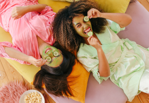 two young women laying on floor with cucumber masks on face